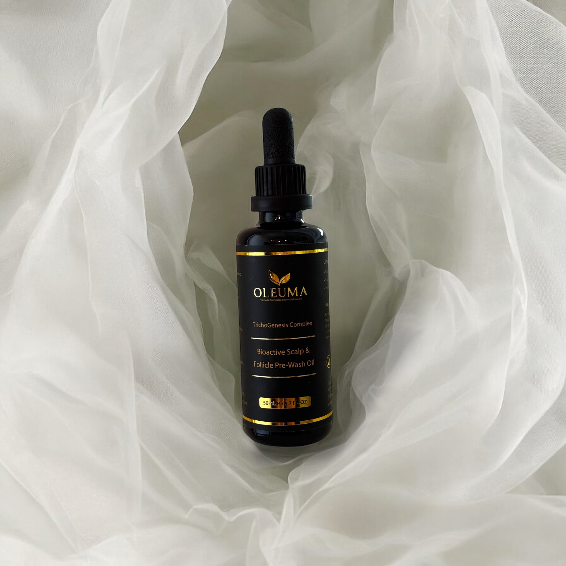 Oleuma hair growth oil bottle wrapped in golden fabric – for scalp nourishment, thickening, and early gray prevention.